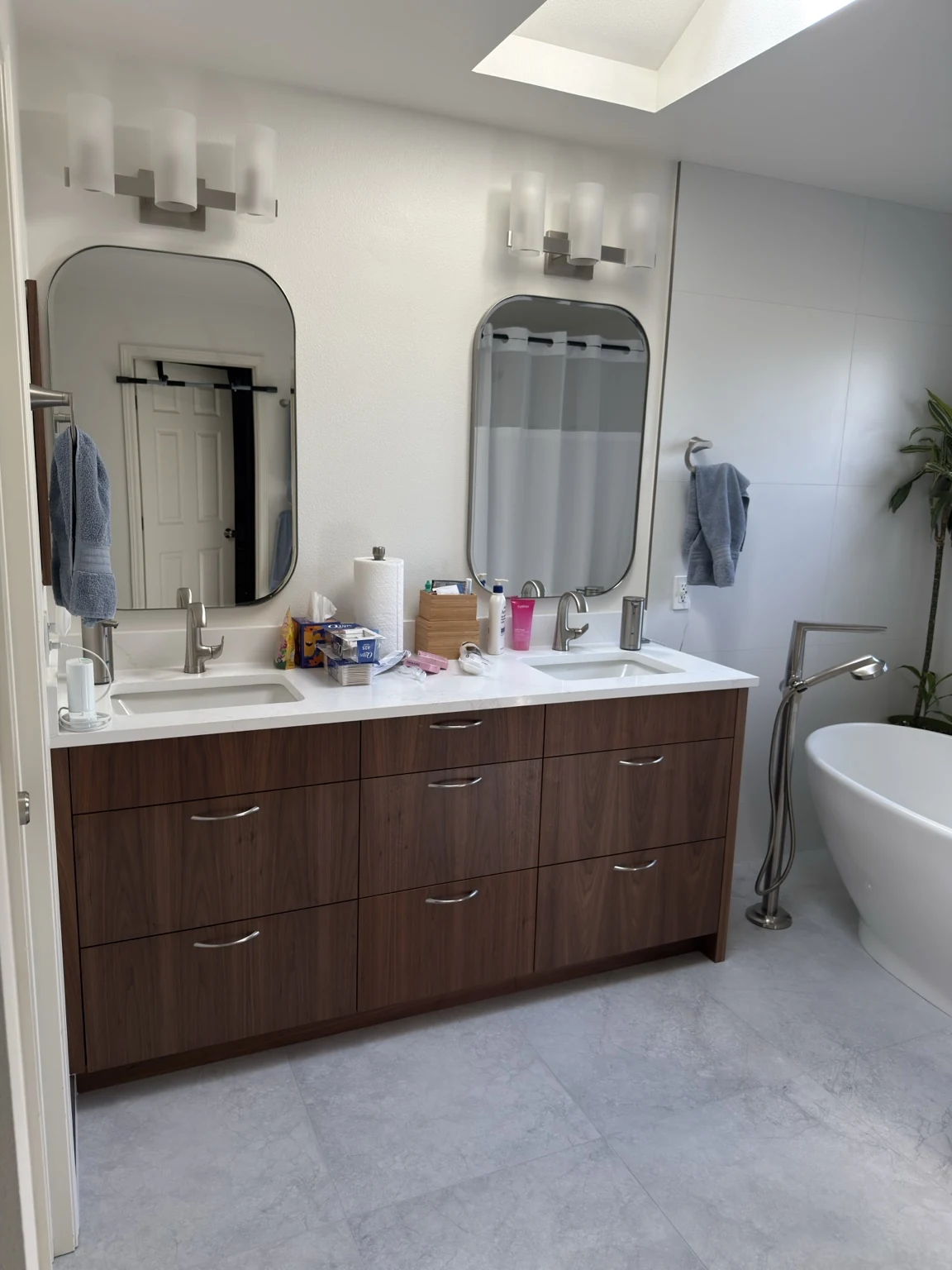 Double-basin bathroom vanity with mirrors and a light tiled floor