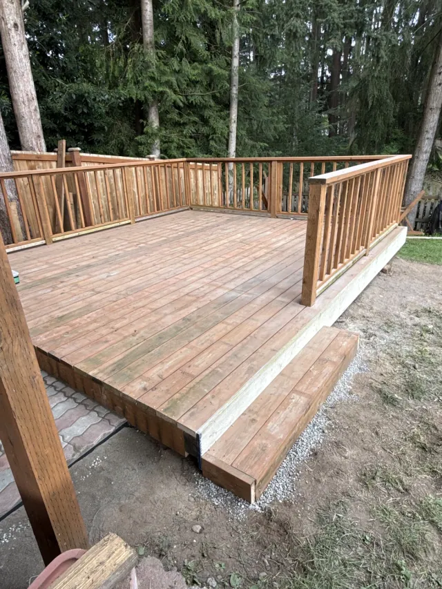 Completed wood deck with vertical wood railings and a wide access step