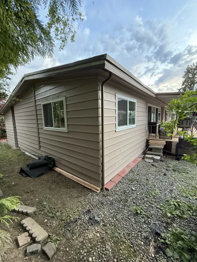 Repainted lap siding with uncovered windows at the side of the home