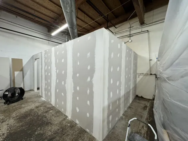 Drywall-covered partition with joint compound at seams and fasteners