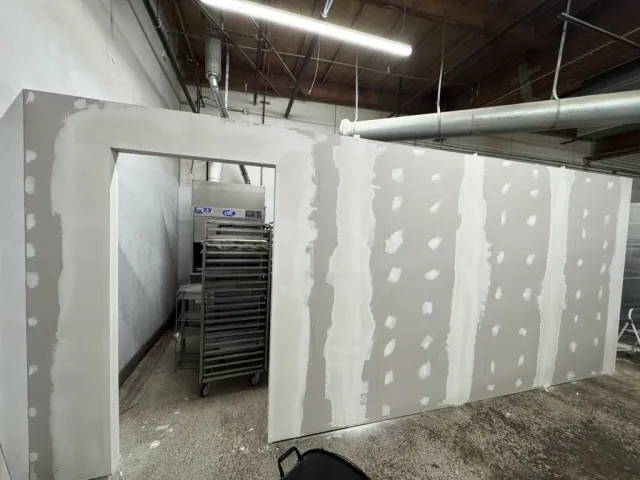 Drywall seams and fastener locations being finished around an opening